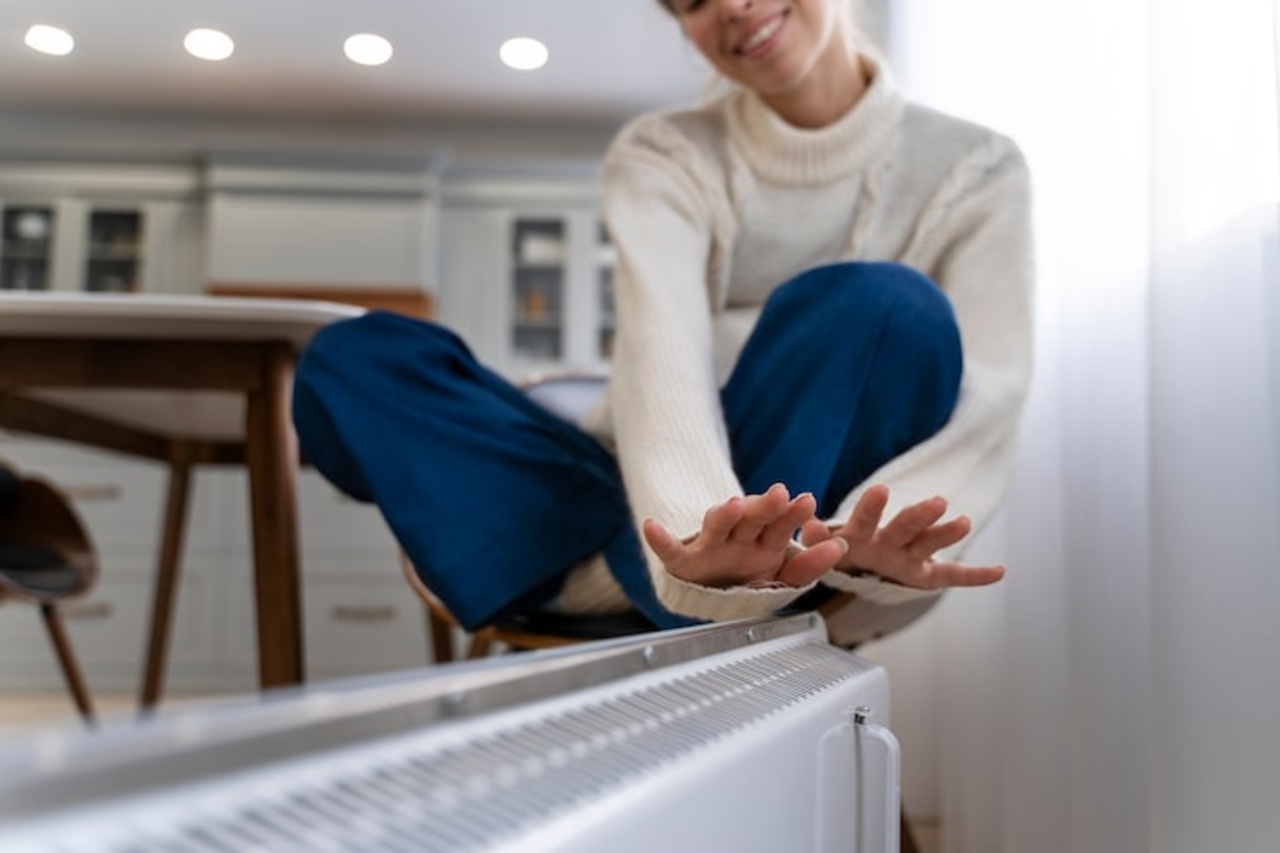 Vrouw warmt zich bij een radiator in huis als symbool voor verwarming en gasenergie
