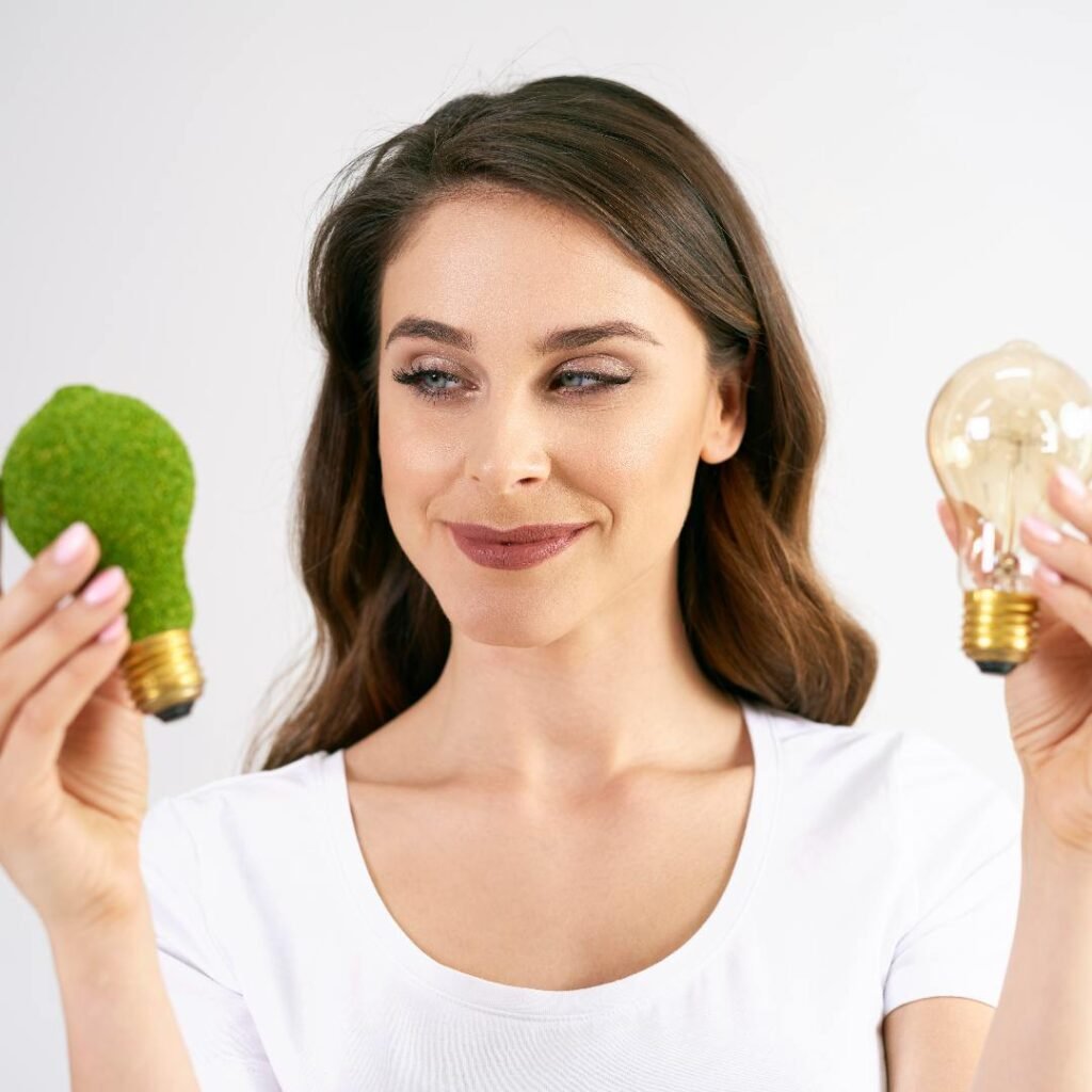 Vrouw vergelijkt een groene en een traditionele gloeilamp. Kiezen tussen duurzame en conventionele energie. Conceptuele afbeelding: groene energie versus traditionele energie. Vrouw met een eco-vriendelijke en een normale gloeilamp. De keuze voor een duurzame toekomst in energie.